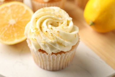 Photo of Tasty cupcake with cream, zest and lemons on board, closeup