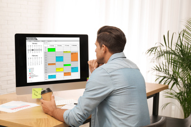 Handsome man using calendar app on computer in office