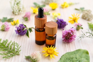Photo of Bottles of essential oil, flowers and herbs on white wooden table, closeup