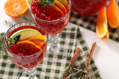 Photo of Christmas Sangria cocktail in glasses and ingredients on white table, closeup. Space for text