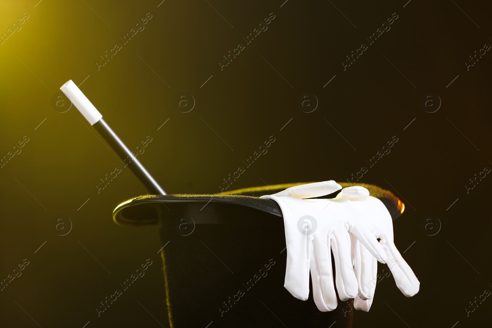 Photo of Magician's hat, wand and gloves on dark background, closeup