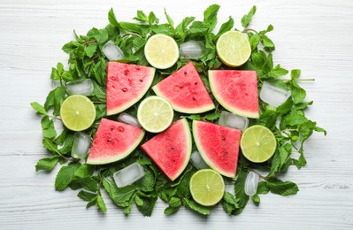 Tasty sliced watermelon, limes, mint and ice on white wooden table, flat lay