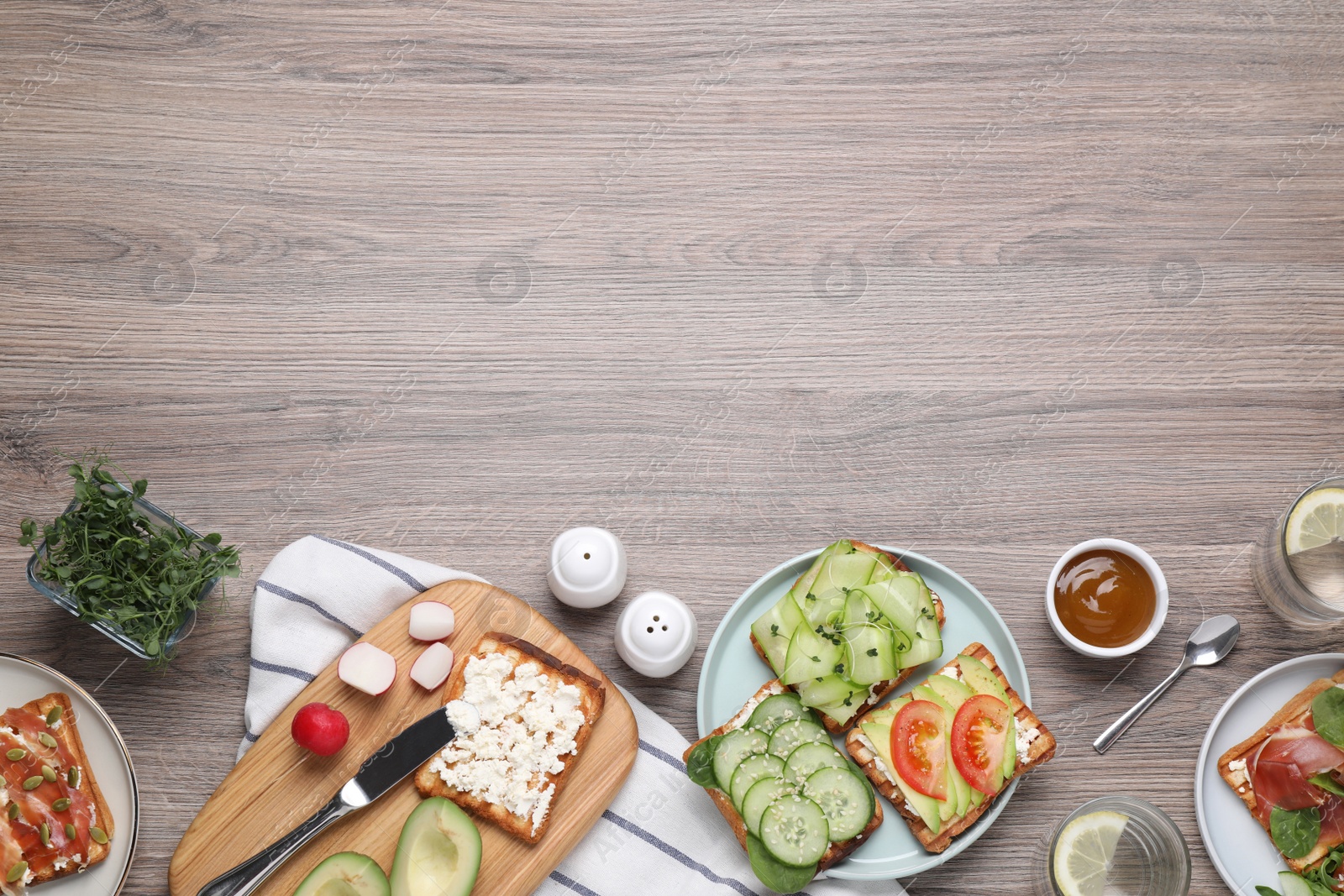 Photo of Different tasty sandwiches served on wooden table, flat lay. Space for text