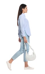 Photo of Young woman with handbag walking on white background
