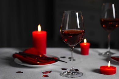 Photo of Romantic table setting with glasses of red wine and burning candles against blurred background
