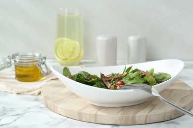 Photo of Delicious salad with beef tongue, arugula, seeds and fork served on white marble table