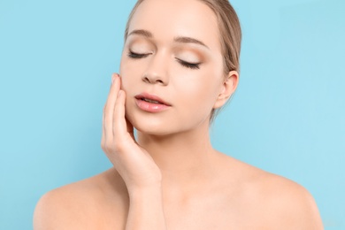 Portrait of young woman with beautiful face on blue background, closeup