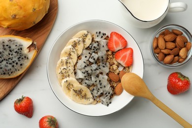 Bowl of granola with pitahaya, banana and strawberry on white marble table, top view