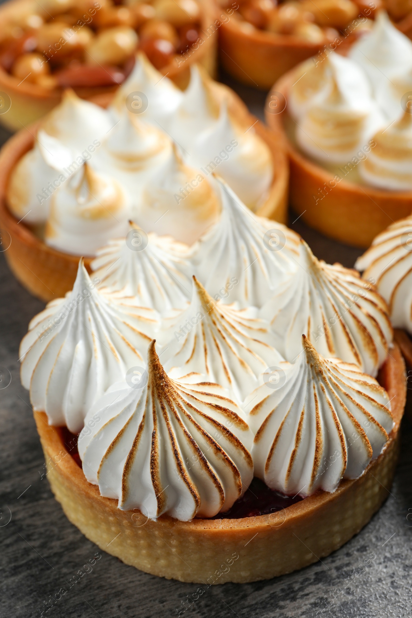 Photo of Many different tartlets on dark grey table, closeup. Tasty dessert