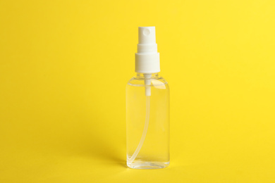 Photo of Spray bottle with antiseptic on yellow background