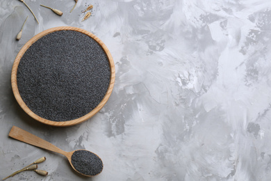 Photo of Dried poppyheads, bowl and spoon with seeds on grey table, flat lay. Space for text