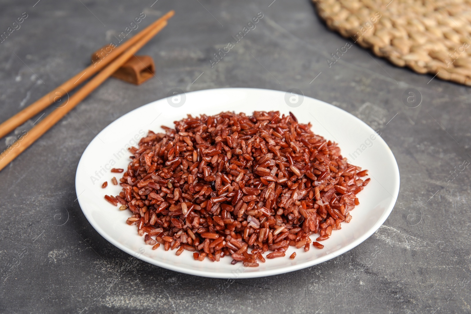 Photo of Plate with delicious cooked brown rice on grey table