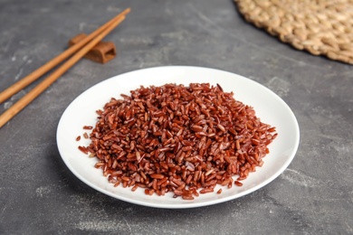 Photo of Plate with delicious cooked brown rice on grey table