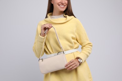 Fashionable young woman with stylish bag on light background, closeup