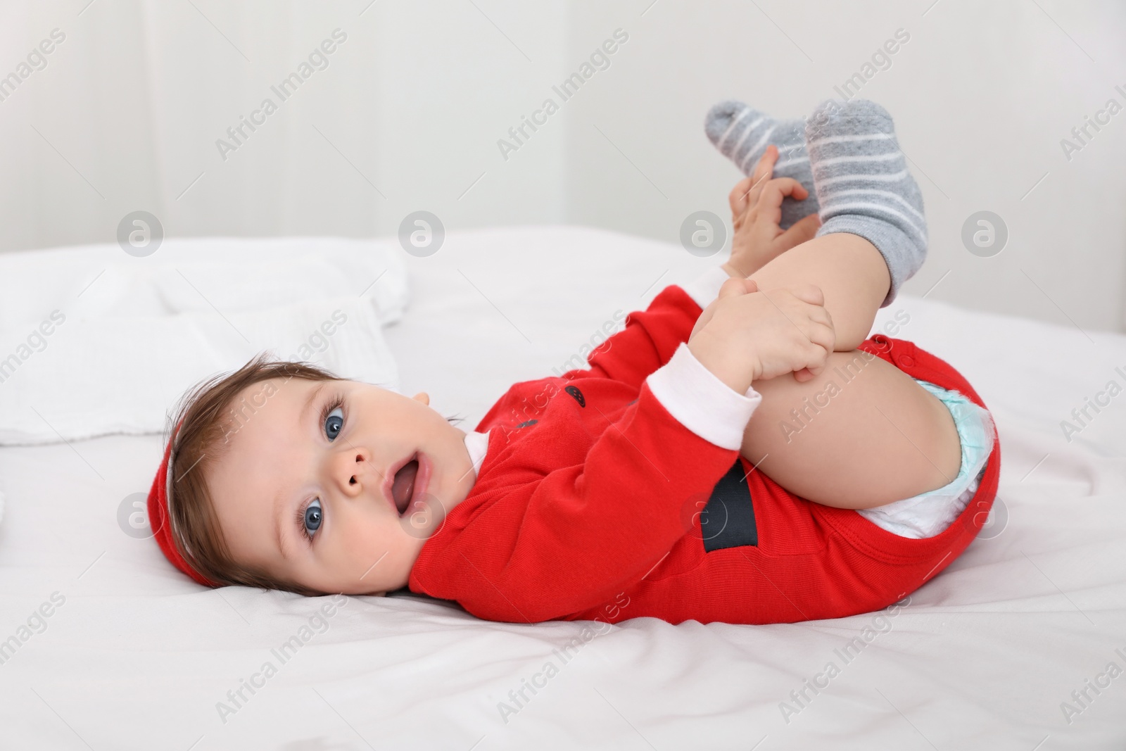 Photo of Cute baby wearing festive Christmas costume on bed