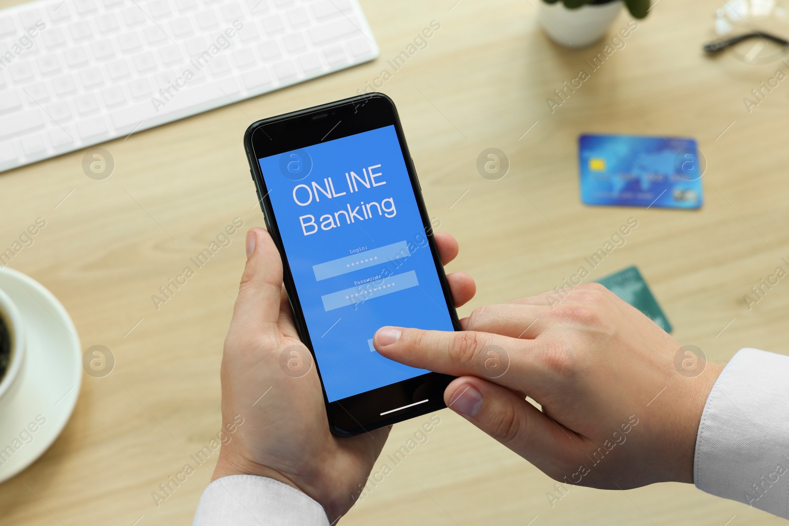 Photo of Man using online banking app on smartphone at wooden office table, closeup