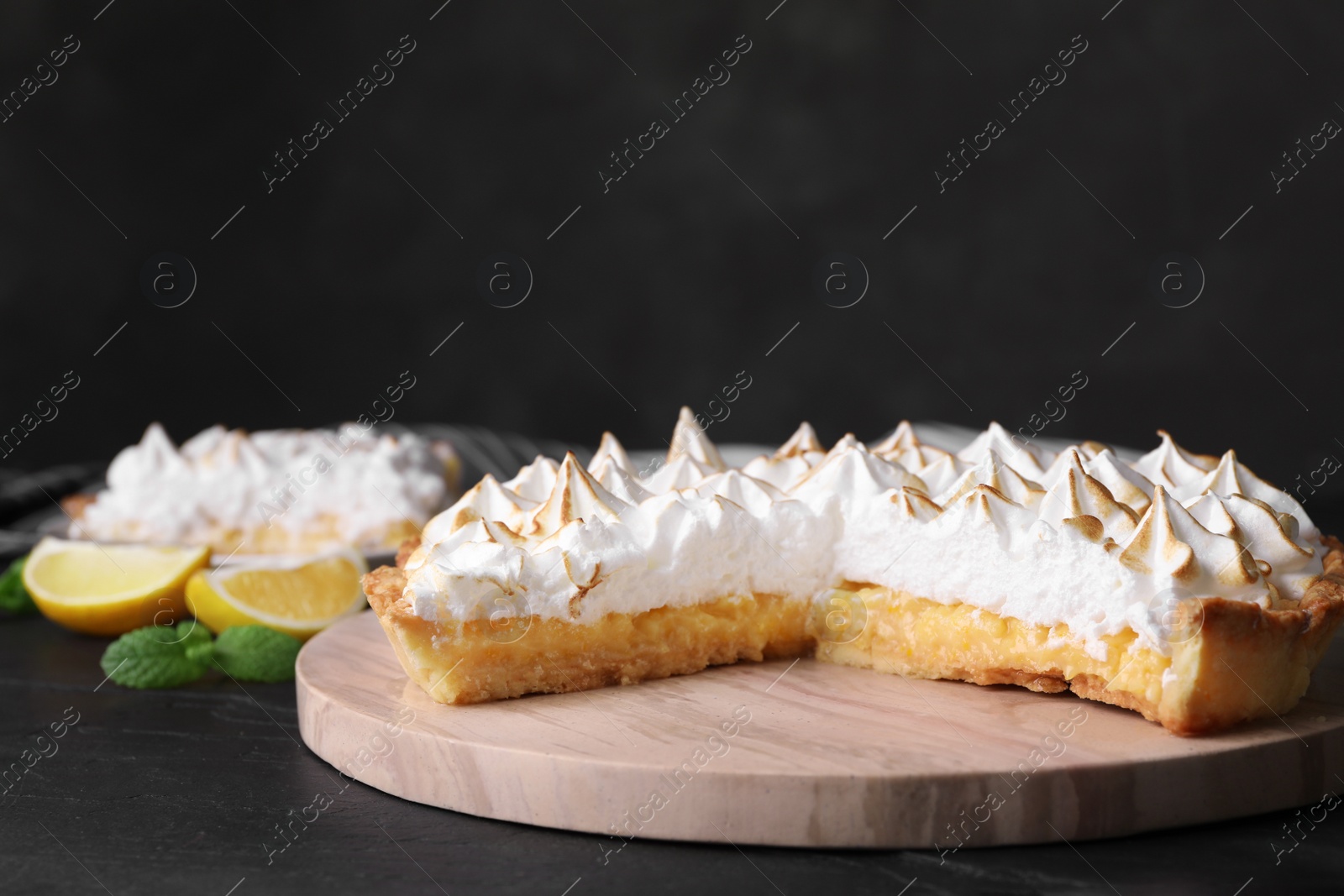 Photo of Serving board with delicious lemon meringue pie on black table