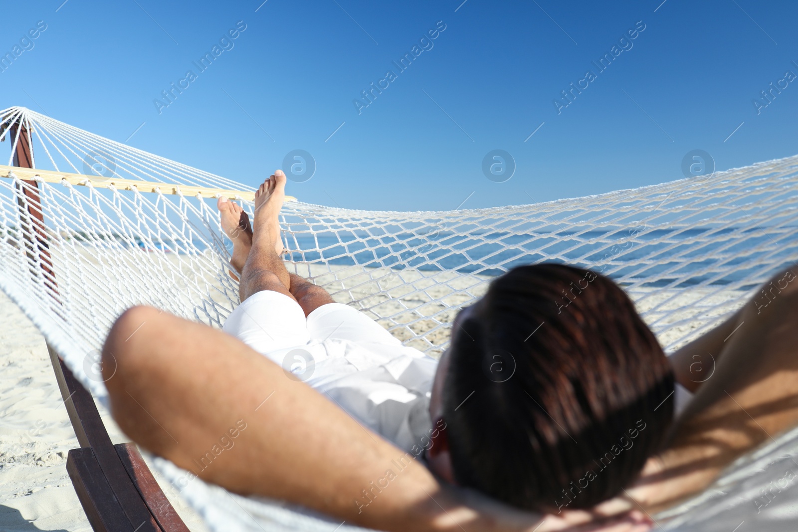 Photo of Man relaxing in hammock on beach. Summer vacation