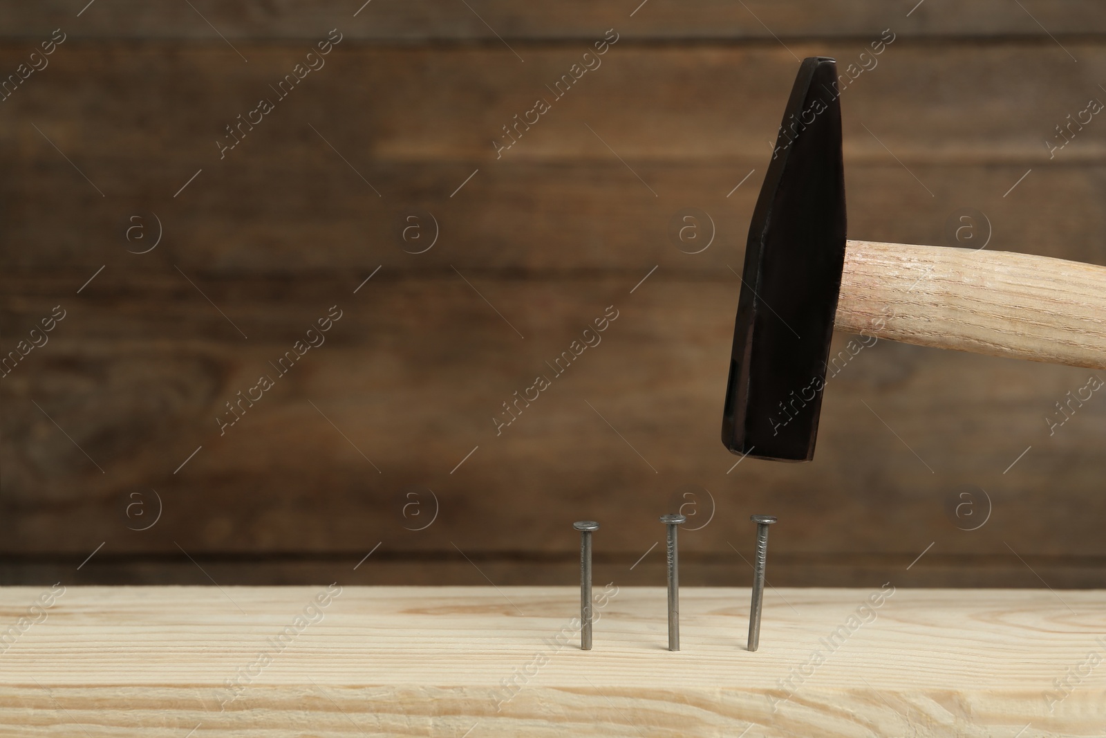 Photo of Hammering nail into plank against wooden background, space for text