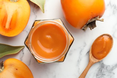 Photo of Delicious persimmon jam and fresh fruits on white marble table, flat lay