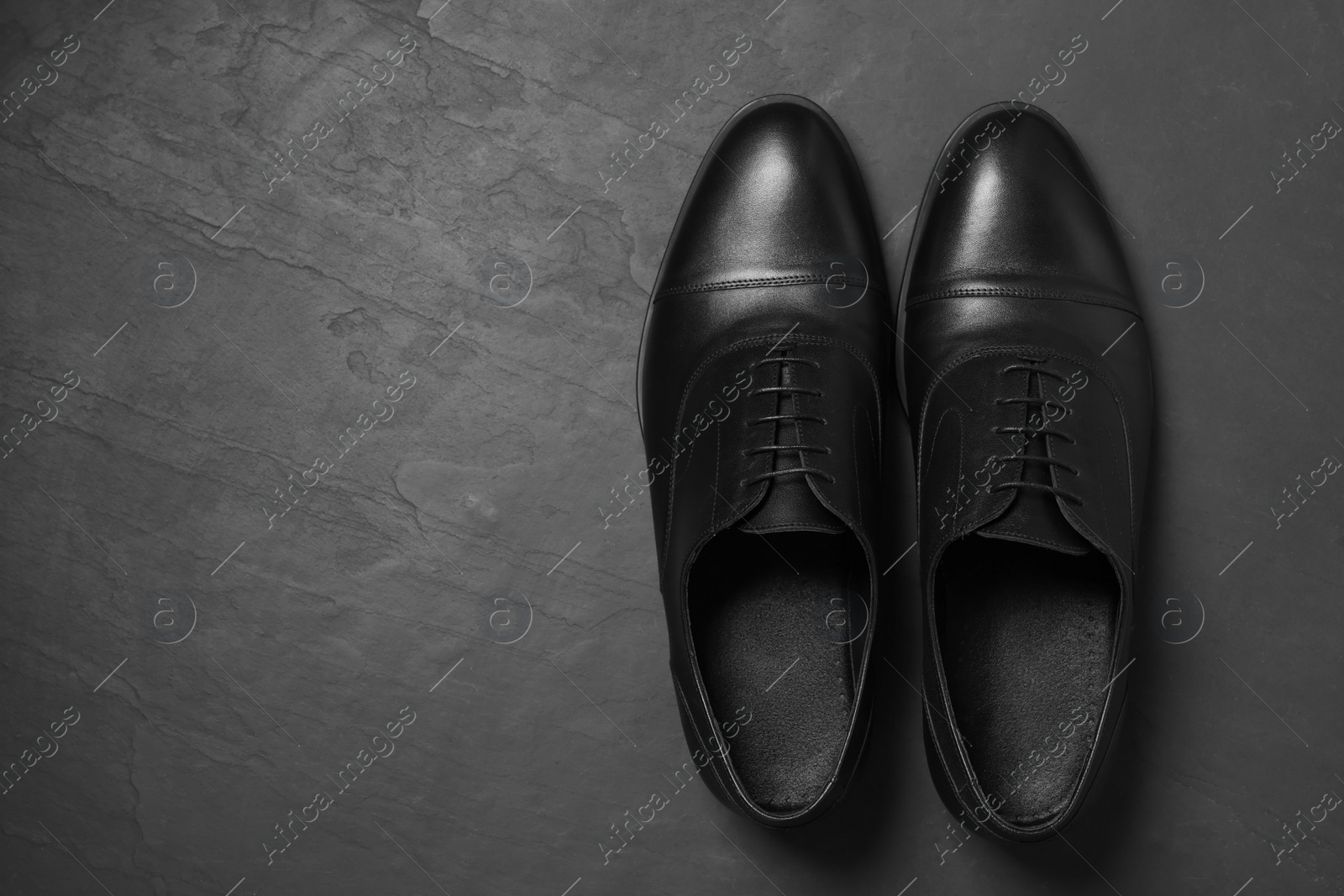 Photo of Pair of leather men shoes on black surface, top view. Space for text