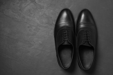 Photo of Pair of leather men shoes on black surface, top view. Space for text