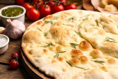 Focaccia bread with rosemary on wooden table, closeup