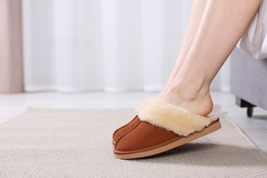 Woman in brown soft slippers at home, closeup. Space for text