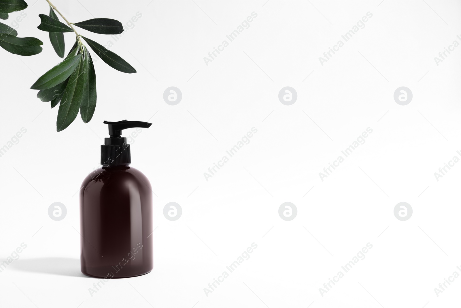 Photo of Bottle with cosmetic product and green leaves on white background, space for text