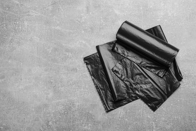 Photo of Black garbage bags on grey stone table, flat lay. Space for text