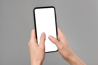 Photo of Woman typing message on smartphone against grey background, closeup