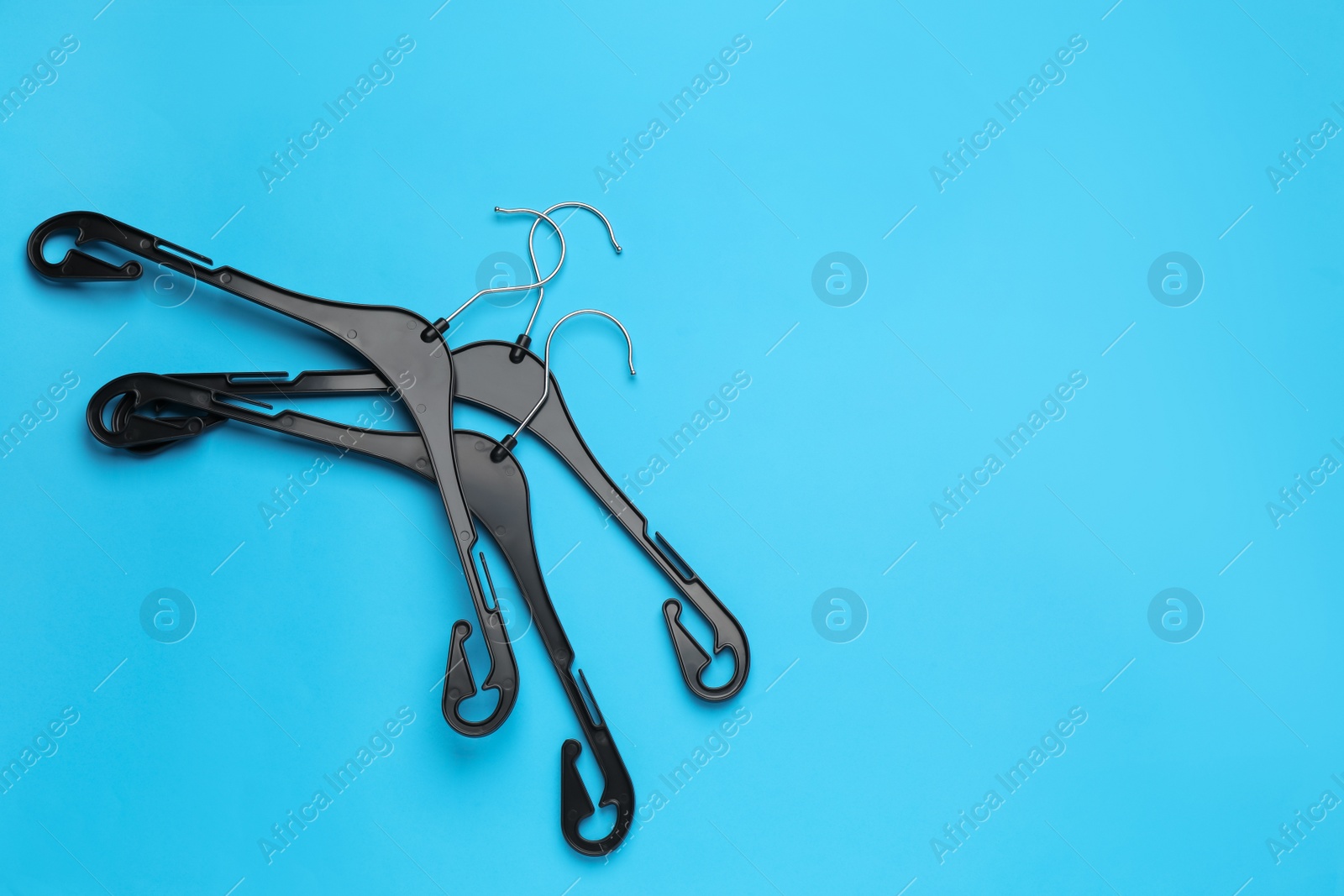 Photo of Empty hangers on light blue background, flat lay. Space for text