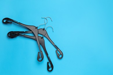 Photo of Empty hangers on light blue background, flat lay. Space for text