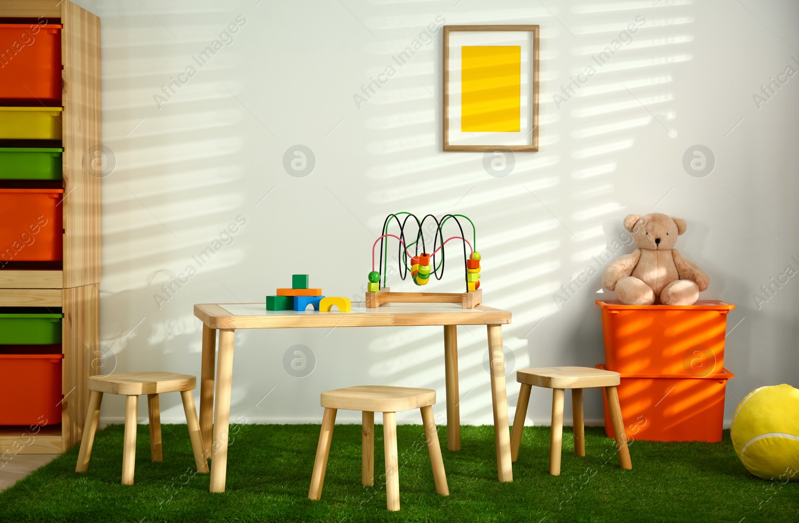 Photo of Stylish playroom interior with wooden table and stools