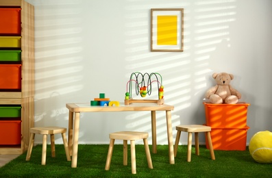 Photo of Stylish playroom interior with wooden table and stools