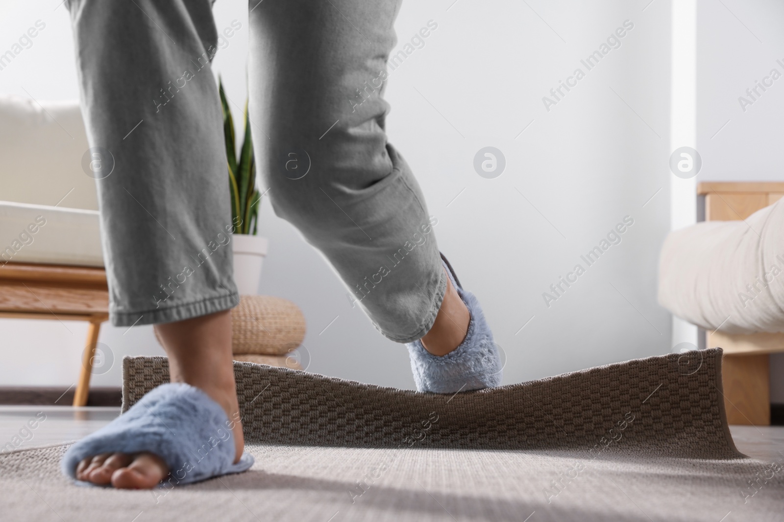 Photo of Woman tripping over carpet at home, closeup