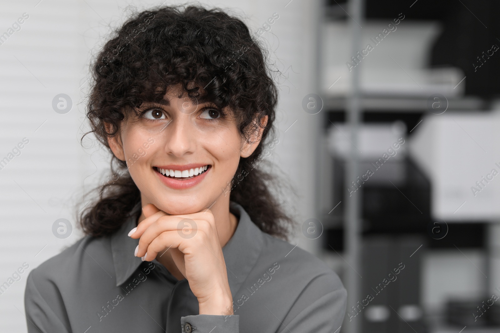 Photo of Portrait of confident entrepreneur or businesswoman indoors. Beautiful lady with curly hair smiling and posing for camera. Space for text
