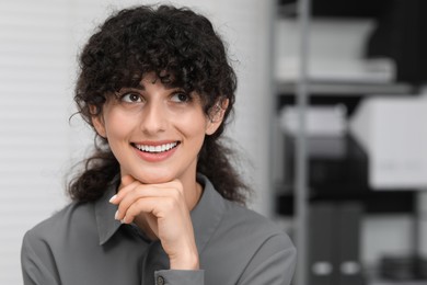 Photo of Portrait of confident entrepreneur or businesswoman indoors. Beautiful lady with curly hair smiling and posing for camera. Space for text