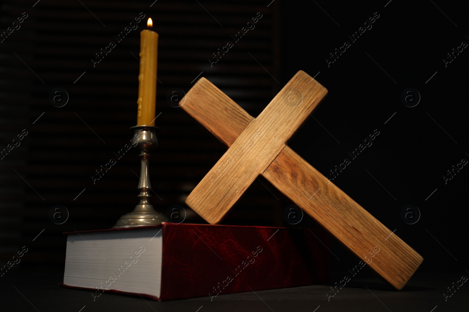 Photo of Church candle, Bible and wooden cross on table
