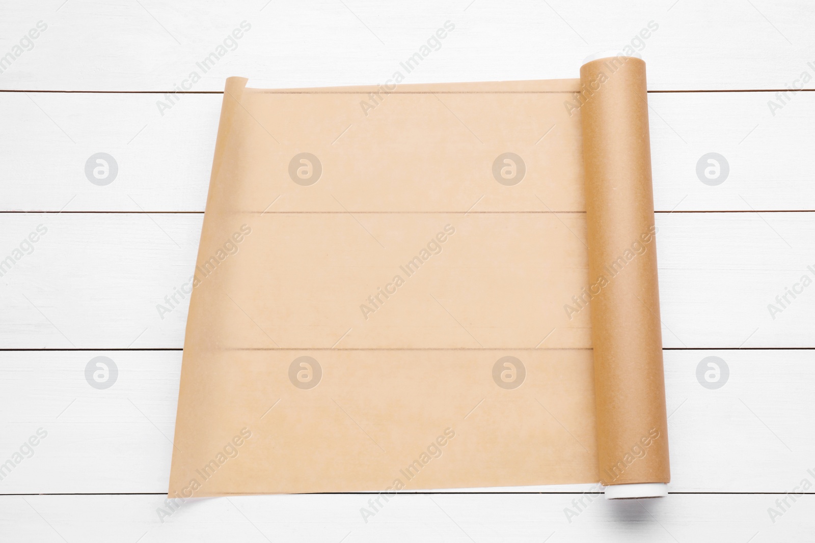 Photo of Roll of baking paper on white wooden table, top view