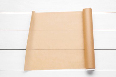 Roll of baking paper on white wooden table, top view