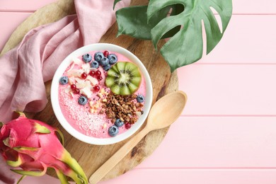 Tasty smoothie bowl with fresh kiwi fruit, berries and granola on pink wooden table, flat lay. Space for text