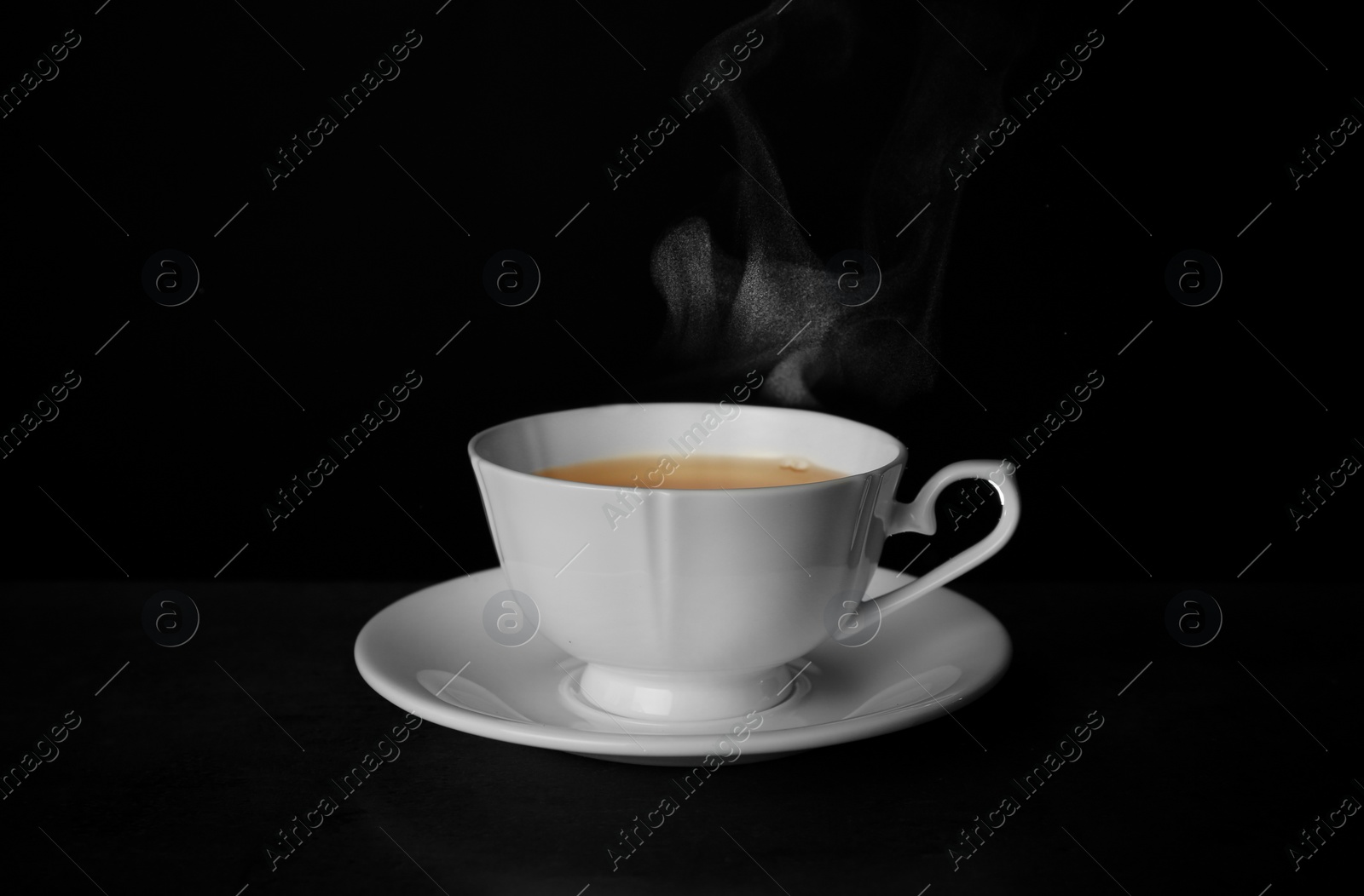 Photo of Ceramic cup of hot fresh tea on table against black background, space for text