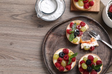 Photo of Delicious tartlets with berries on wooden table, flat lay