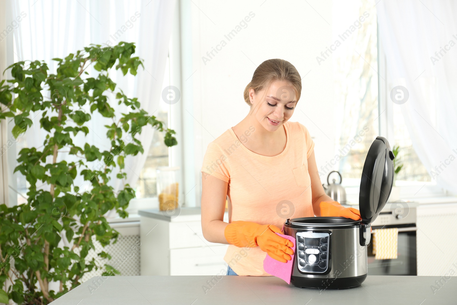 Photo of Young woman cleaning modern multi cooker in kitchen