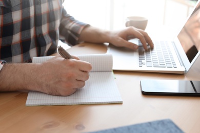 Photo of Young man working with laptop at desk. Home office