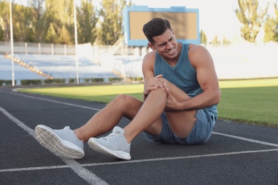 Photo of Man in sportswear having knee problems at stadium