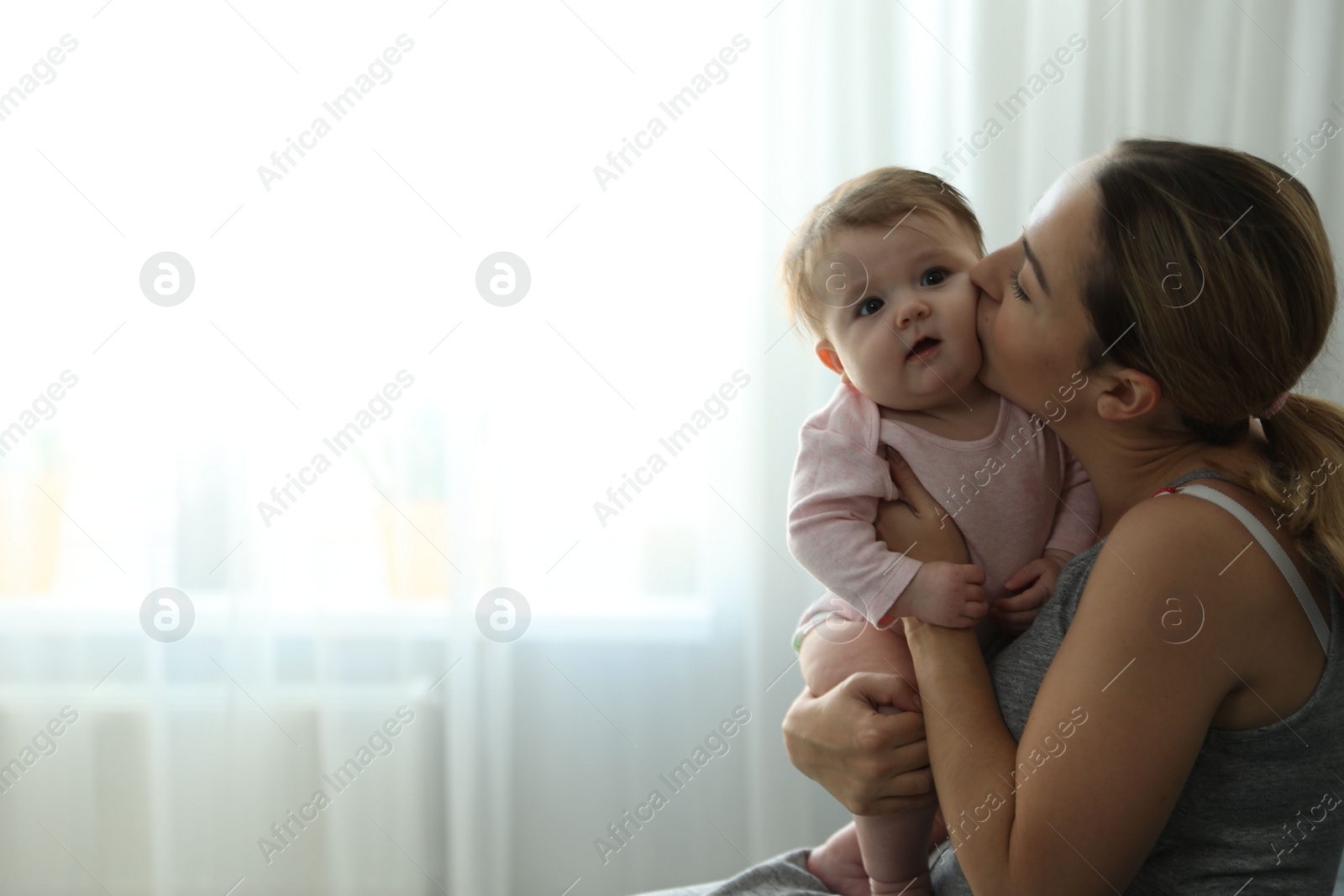 Photo of Young woman with her cute baby at home. Space for text