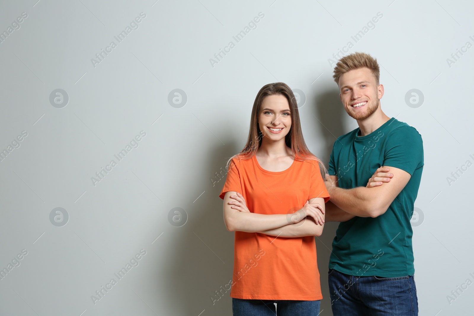 Photo of Young couple wearing blank t-shirts on light background. Mockup for design