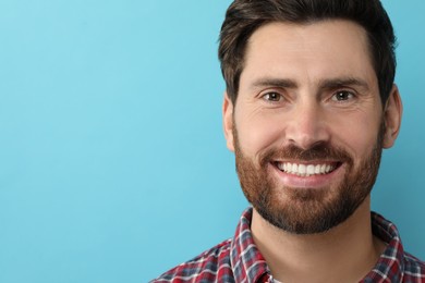 Portrait of smiling man with healthy clean teeth on light blue background, closeup. Space for text